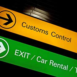 An airport sign directing travellers to the customs desk as well as where to go to pick up their rental vehicle.