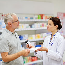An older gentleman chatting with his pharmacist about his prescription medication.
