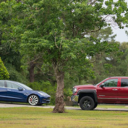 A car and a pick up truck sitting in a driveway.