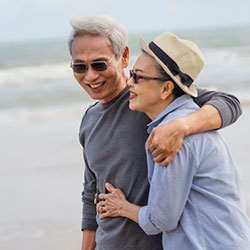 A mature couple hugging as they walk along a beach.